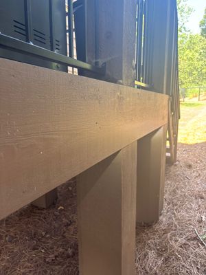Concrete void-fill work is visible under a structure's foundation beam, with support posts and concrete being installed