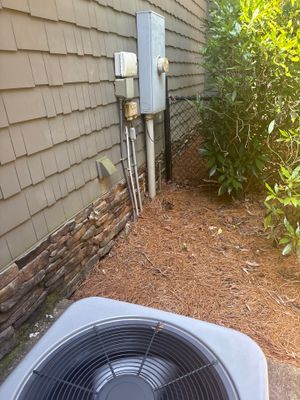An exterior HVAC condenser unit is positioned near the foundation with an outdoor drainage system installation in