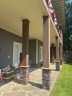 Completed patio installation with new stone/concrete flatwork, decorative columns, and restored landscaping around a