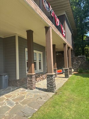Completed foundation and patio work showing a newly installed stone/concrete flatwork patio with drainage system and