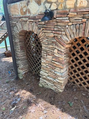 Exterior foundation view showing exposed stone/brick masonry with installed drain boxes and grates at the base,