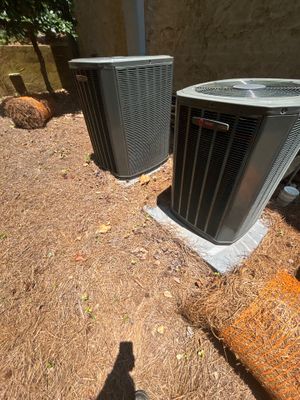 Two HVAC condenser units installed on concrete pads with exterior yard drainage infrastructure visible in the