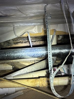 Interior drainage pipes and materials staged in a crawl space or basement during installation, with white PVC or