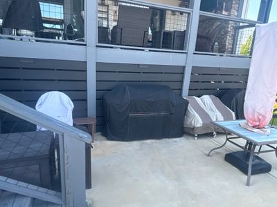 A covered outdoor patio or deck area with furniture and equipment staged, showing no visible foundation repair or