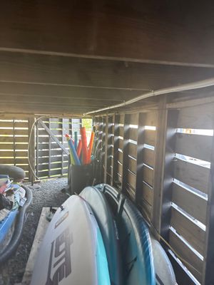 Interior storage or utility space with wooden storage cabinets, kayaks/boards, and miscellaneous items stacked on the