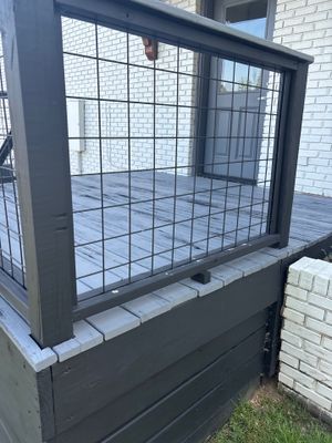 Installation of a black steel wall-anchor system with horizontal grid pattern across a foundation opening, with