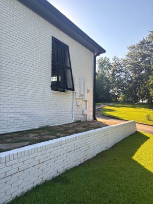Completed yard drainage installation showing a new brick retaining wall or foundation edging along the perimeter of a