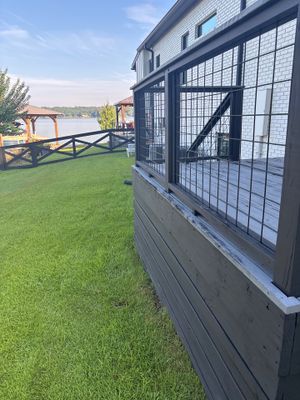 A completed lakeside residential property showing a newly constructed home with black metal window grilles, manicured