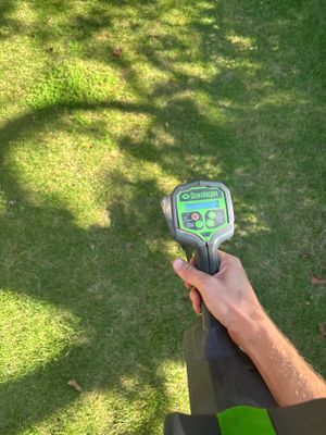 A Sentricon moisture meter is being used to assess soil moisture levels in a lawn, likely as part of a pre-inspection