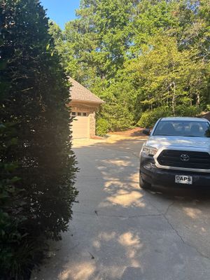 A residential driveway and garage structure surrounded by mature trees with no visible foundation repair or