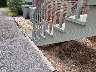 Exterior foundation work showing installed deck/platform with gray composite decking and railing system, alongside