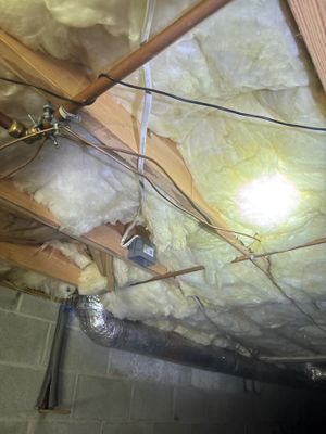 Crawlspace encapsulation work in progress showing fiberglass insulation batts installed between floor joists,