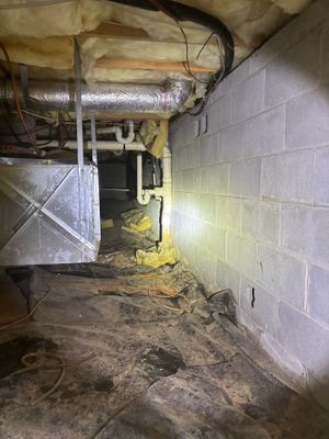 A crawlspace or basement foundation area with interior drainage piping installed along the perimeter, yellow