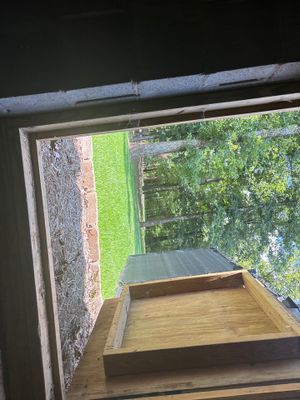 An exterior drainage system installation in progress showing a wooden catch basin or drain box positioned in a grassy