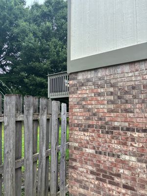 A residential foundation showing a brick basement wall adjacent to a wooden fence and modern siding, with no visible