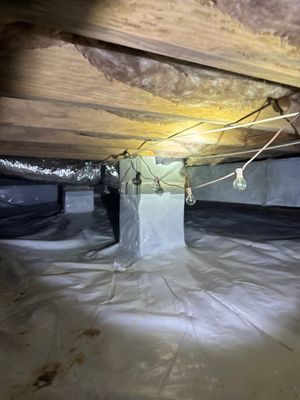 A crawlspace encapsulation and interior drainage system installation in progress, showing plastic vapor barrier on the
