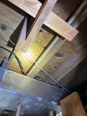 Interior crawlspace or basement showing active drainage installation with piping, support structures, and fill material