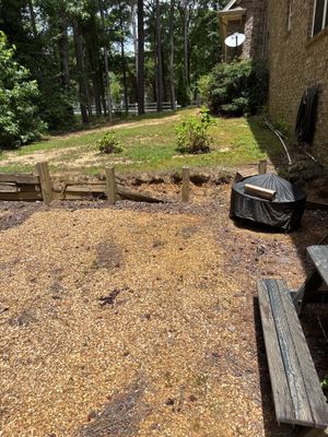 Exterior ground-level view of a residential property showing a gravel/stone patio area with wooden benches and