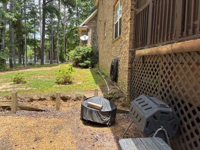 Exterior view of a brick house with yard, deck, and landscaping showing no visible foundation repair or waterproofing