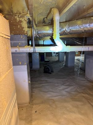A crawlspace or basement interior showing an installed interior drainage system with visible piping and a sump