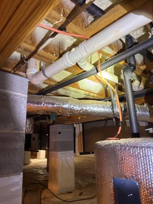 A crawl space showing installed interior drainage piping along the foundation perimeter and partial crawl space