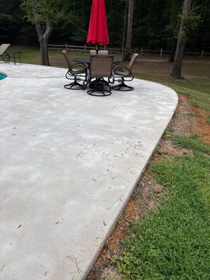 A completed concrete patio slab with furniture and umbrella installed, showing finished concrete flatwork in a