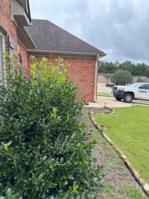 A clean exterior view of a brick residential home with manicured landscaping, lawn, and a parked truck, showing no