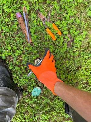 A worker in an orange safety glove is installing or positioning a catch basin or yard drainage component in an actively