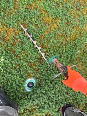 Aerial view of yard drainage installation in progress showing a drainage line laid across a lawn with collection basin
