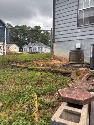 Exterior yard drainage work in progress showing excavation and installation of a catch basin or drainage system in the