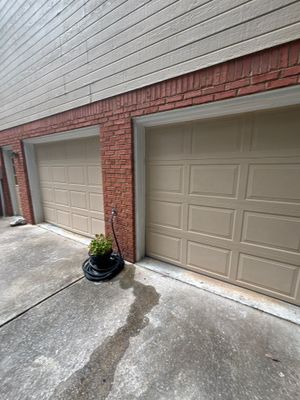 Clean exterior view of a residential garage with two white panel doors and red brick facade, showing no visible
