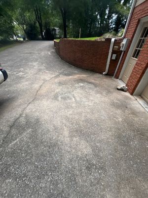 Exterior view of a brick building with an asphalt driveway and yard showing no visible foundation repair work, drainage