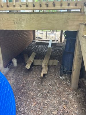 Crawlspace interior showing drainage channel installation along the foundation perimeter with wooden posts and beam