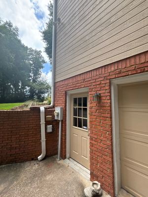 Exterior foundation area showing white PVC drainage pipe and yard drainage installation in progress against a brick