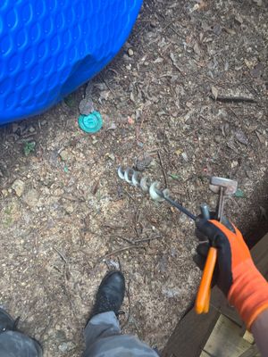 Outdoor drainage installation in progress with a blue basin, drainage pipe, and crew member in orange safety gear