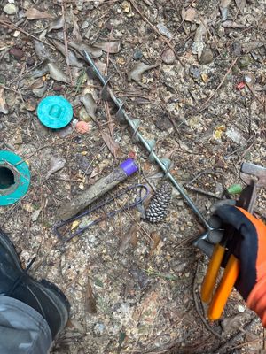Exterior job site showing drainage tools and equipment staged on soil with blue drainage basin components visible,