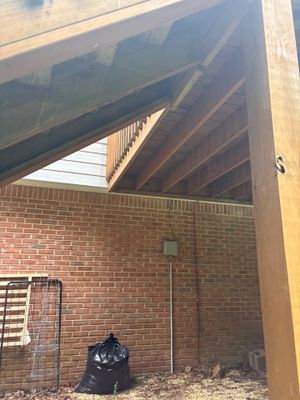 A brick foundation wall with newly installed wooden beam supports and interior drainage system preparation visible,