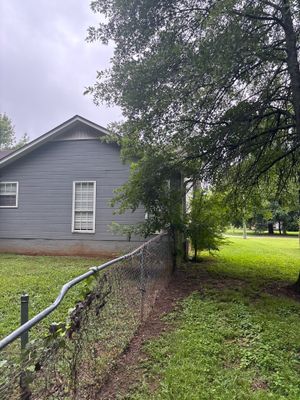 Exterior view of a residential home with a metal fence and landscaped yard showing no visible foundation repair or