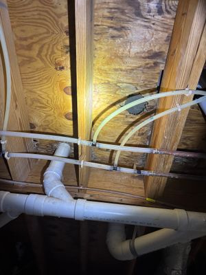 Interior drainage system installation in progress showing white PVC drainage pipes and tubing routed along the