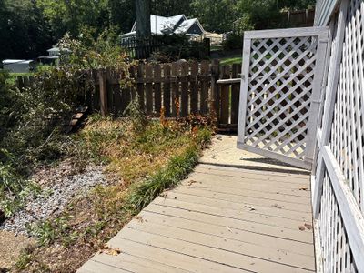 Exterior view of a residential deck and yard with landscaping, gravel, and wooden lattice screening showing no visible