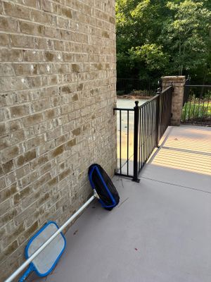 Exterior deck area with yard drainage equipment staged, showing blue drain pipe and catch basin apparatus positioned