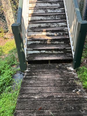 A wooden boardwalk or bridge structure with visible wood rot, deterioration, and moisture damage, showing the