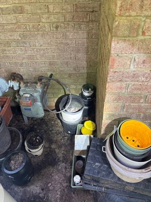 Foundation repair job site showing staged equipment and materials including buckets, drainage components, and what