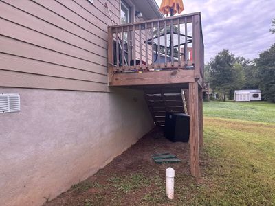Exterior view of a house foundation with a white PVC drainage pipe installed in the yard, showing pre-work or