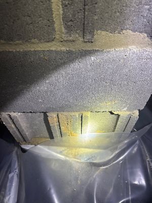 Interior basement or crawl space showing installed interior drainage channel along the foundation perimeter with