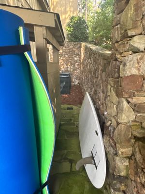 Exterior narrow alleyway or foundation trench with blue and green drainage pipes staged against a stone foundation
