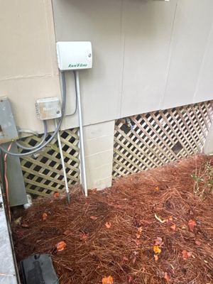 Exterior crawlspace or foundation area with fresh mulch/wood chips and visible drainage or discharge line installation