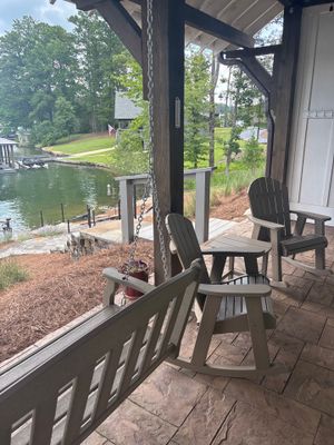 A covered porch or deck overlooking a waterfront property with Adirondack chairs, showing the exterior setting with no