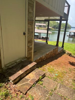 Exterior view of a foundation with visible soil erosion and a drainage channel or trench dug along the perimeter near