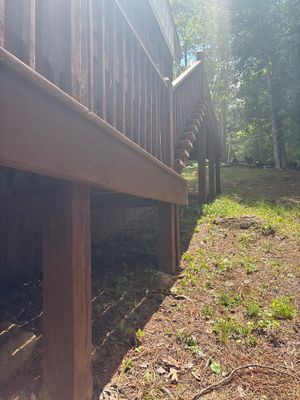 Exterior view of a residential structure with exposed undercarriage/crawlspace and surrounding wooded landscape showing